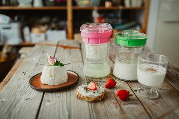 Mesa de desayuno abundante con quesos y yogures caseros hechos con el fermentador de queso de Kéfir Kefirko, junto a fruta fresca y pan.