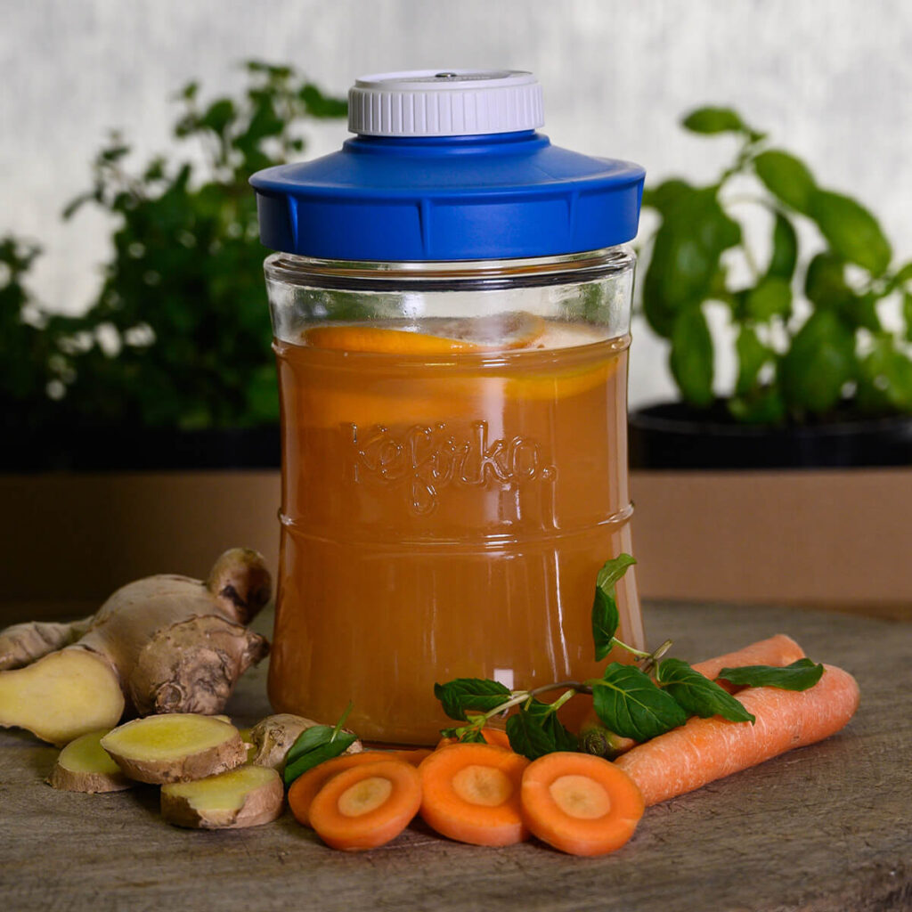 Botella para fermentación Kefirko con una bebida de naranja, jengibre, zanahoria y menta.
