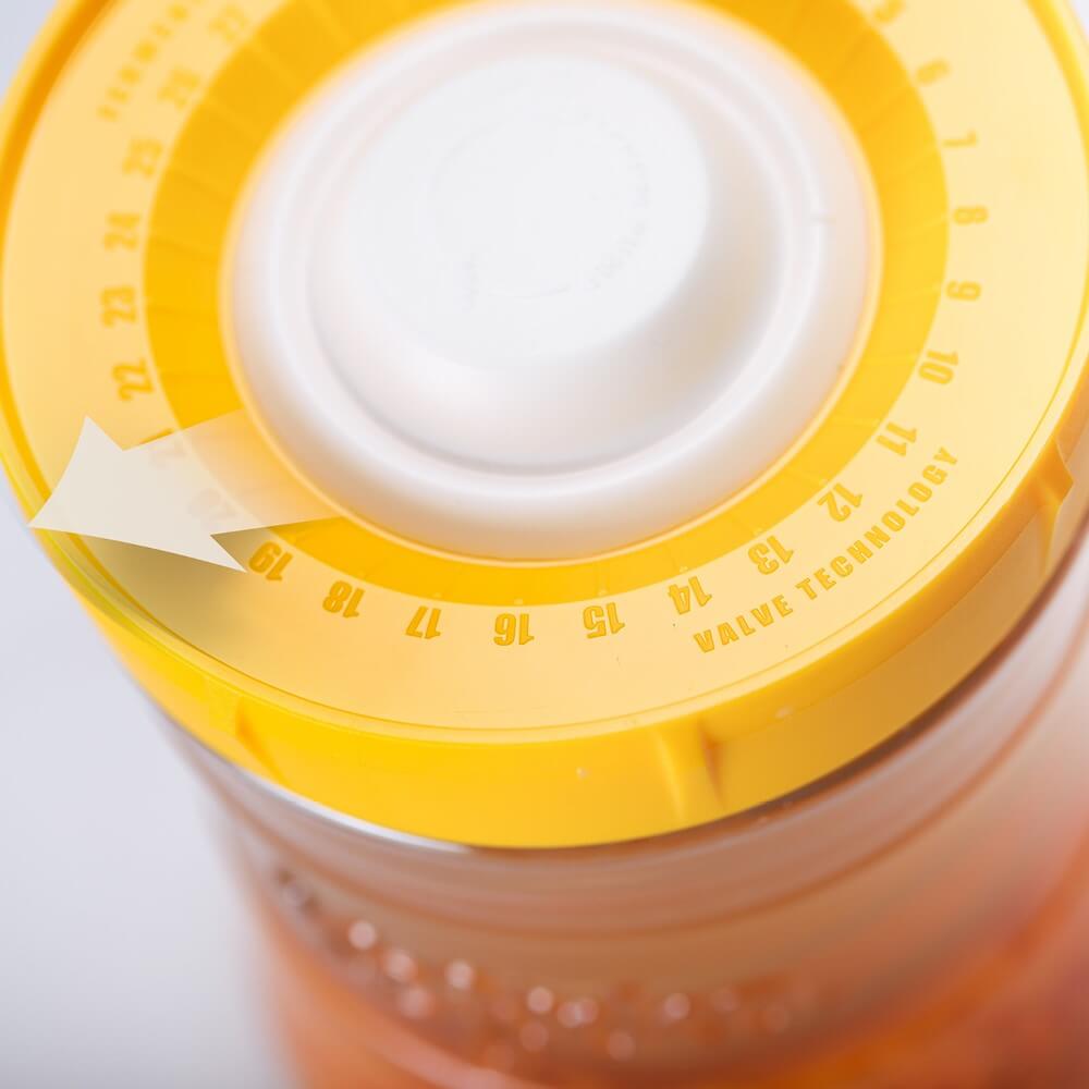 Primer plano de la tapa amarilla de un tarro de fermentación con contador de días y tecnología de válvula.