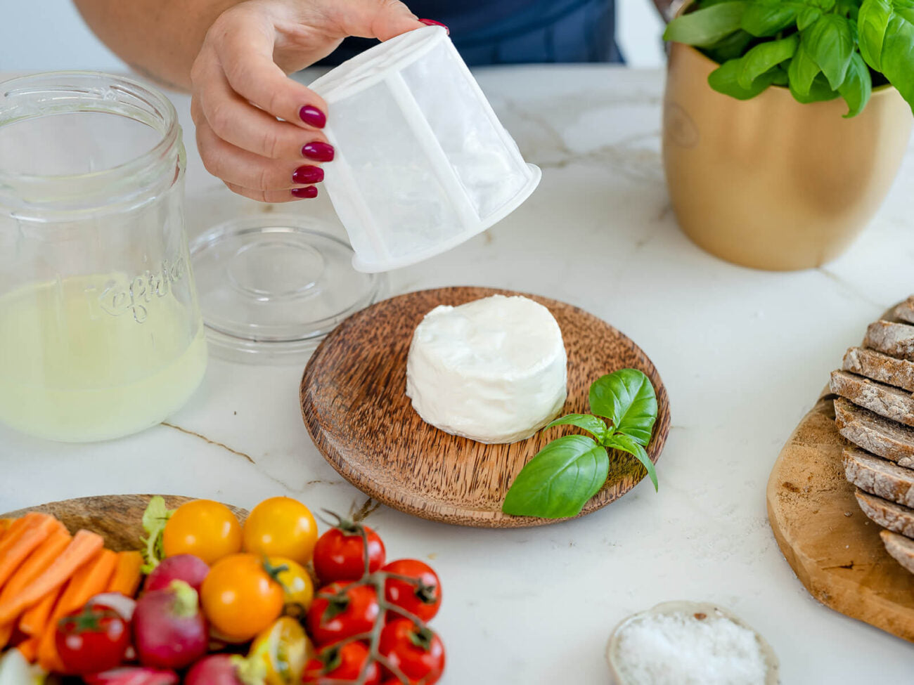Mano desmoldando un queso fresco circular, preparado con el fermentador de queso de Kéfir Kefirko, sobre una tabla de madera rústica.