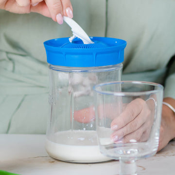 Persona separando los gránulos de la tapa coladora con un utensilio para preparar una nueva tanda de kéfir casero.