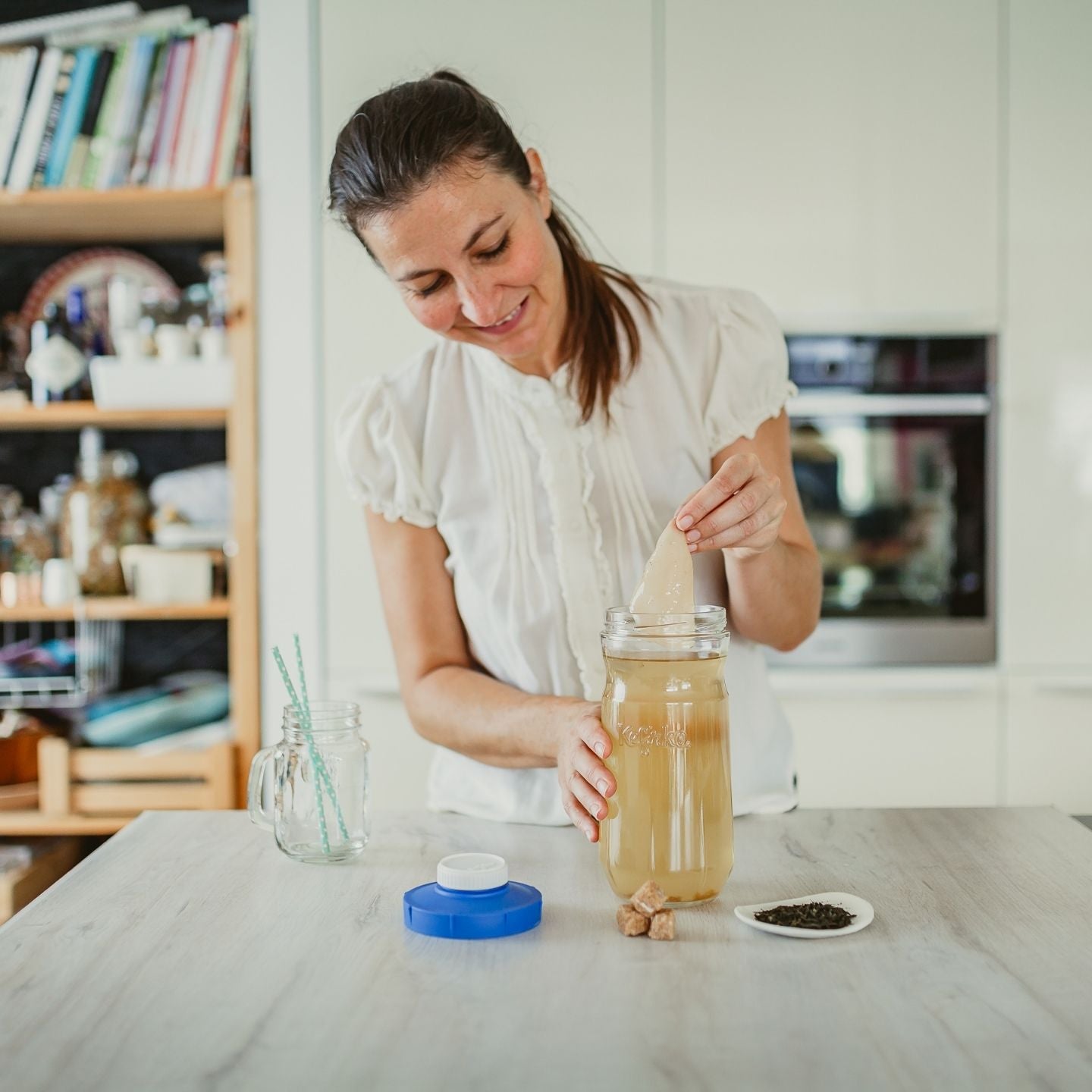mujer sacando el scooby de kombucha de tarro de cristal